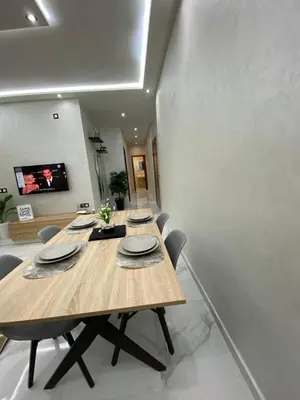 a dining room with a wooden table and chairs at Appartement lux résidence fermée sécurisé parking gratuit in Fès