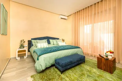 a bedroom with a large bed and a blue ottoman at Villa Stevana in Oulad Mazoug