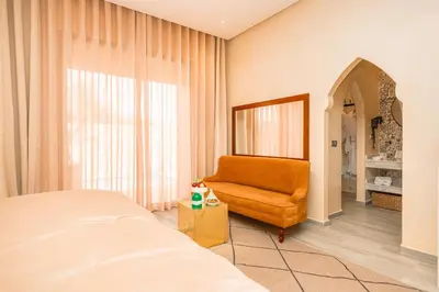 a bedroom with a bed and a chair and a window at Villa Stevana in Oulad Mazoug