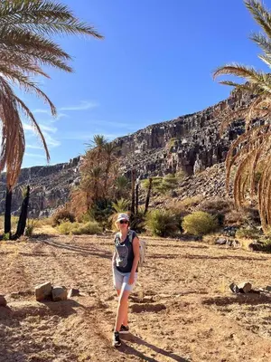 a woman walking on a dirt road near a mountain at Gite d'tape handour in Hamdour