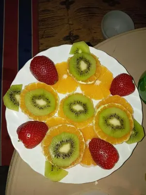 a plate of fruit with kiwi oranges and strawberries at Gite d'tape handour in Hamdour