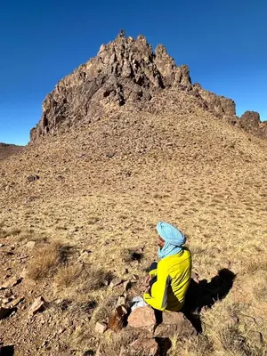 a person sitting on a rock in front of a mountain at Gite d'tape handour in Hamdour