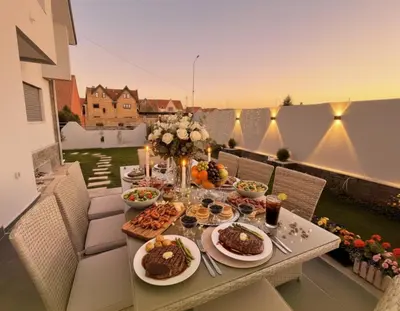 a table filled with food on a balcony with the sunset at Villa Lumiere-Luxury Retreat with Private Spa and Garden in Ifrane