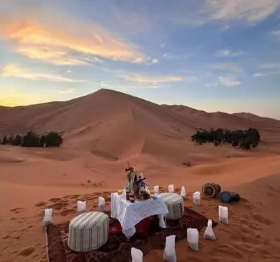 a table in the desert with a mountain in the background at Desert Marhaba luxury Camp in Merzouga