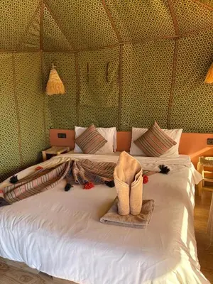 a bedroom with a white bed with a hat on it at Merzouga sands camp in Merzouga