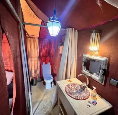 a room with a bathroom with a toilet and a lamp at Merzouga sands camp in Merzouga