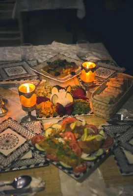 a table with plates of food and candles on it at Merzouga sands camp in Merzouga