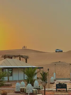 a building in the desert with a car in the background at Merzouga sands camp in Merzouga