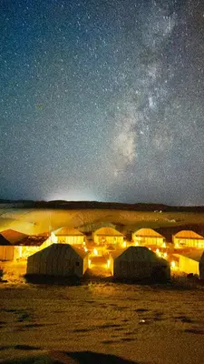 a group of tents under a starry sky at night at Merzouga sands camp in Merzouga