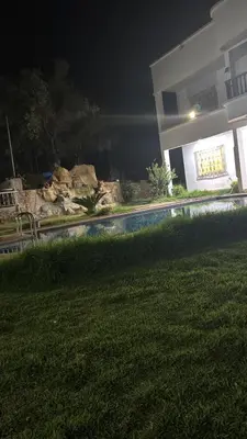 a house with a swimming pool at night at Ferme Erraha in Bhalil