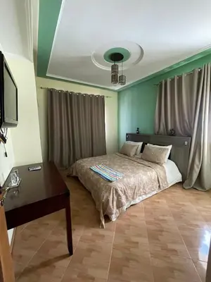 a bedroom with a bed and a table and a tv at Ferme Erraha in Bhalil
