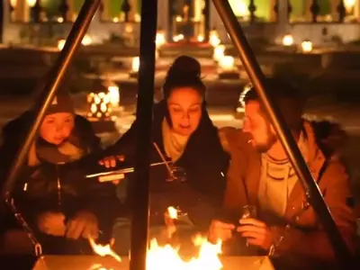 a group of people sitting aroundburning fires at night at Luxury Dune's Camp in Merzouga