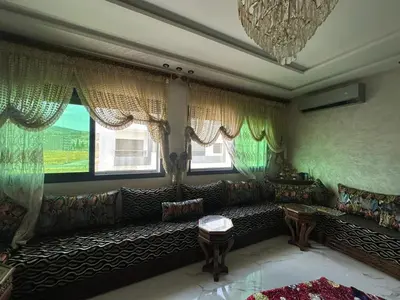 a living room with a couch and two windows at l'habitation avec la famille in Fès