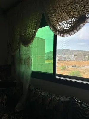 a window with a curtain and a view of a field at l'habitation avec la famille in Fès
