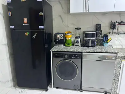 a kitchen with a washing machine and a refrigerator at l'habitation avec la famille in Fès