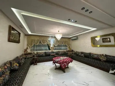 a large living room with couches and a table at l'habitation avec la famille in Fès