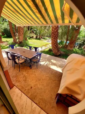 a patio with a table and chairs under an umbrella at Marrakech LUXE in Oulad Akkou