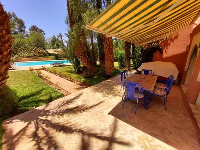 a patio with a table and chairs and a pool at Marrakech LUXE in Oulad Akkou