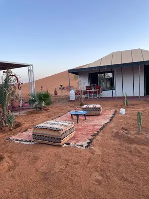 a building in the middle of the desert with a table at Merzouga in Merdani