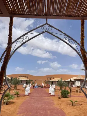 an archway with chairs and tables in the desert at Merzouga in Merdani