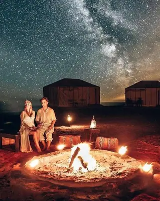 a man and a woman sitting next to a fire at Tilila Luxury Camp in Merzouga