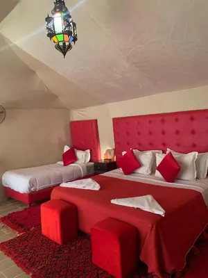 a bedroom with two beds with red furniture and a chandelier at Tilila Luxury Camp in Merzouga