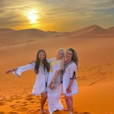 three girls in white dresses standing in the desert at Tilila Luxury Camp in Merzouga