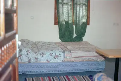 a small bed in a room with a table at le sirwa salam in Anzel