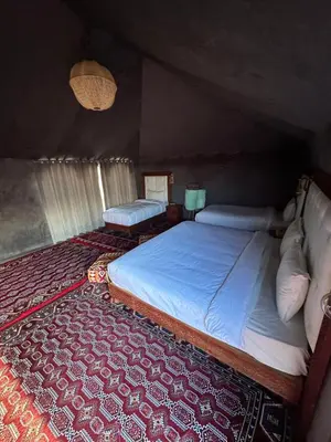a bedroom with two beds and a red carpet at Fabulous Luxury Camp in Merzouga