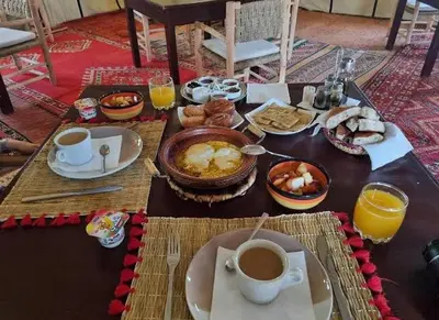 a table with breakfast foods and coffee on it at Fabulous Luxury Camp in Merzouga