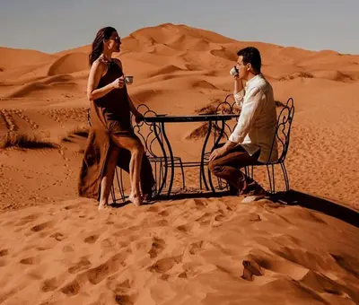 a man and a woman sitting on a bench in the desert at Fabulous Luxury Camp in Merzouga