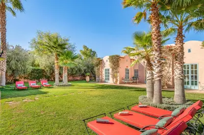 a group of red chairs and palm trees in a yard at Villa Cannella - Marrakech in Chaibate