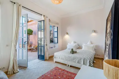 a white bedroom with a bed and an open door at Villa Cannella - Marrakech in Chaibate