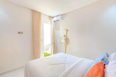 a white bedroom with a bed and a window at Grand Appartement avec Balcon Marrakech in Oulad Akkou