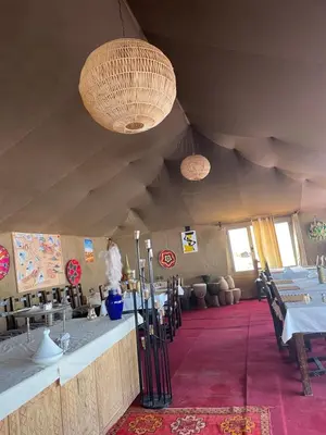 a room with tables and chandeliers in a tent at Luxury Desertcamp in Merdani