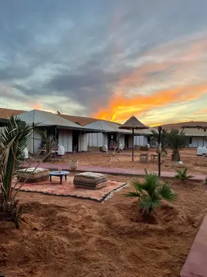 a building in the desert with a sunset in the background at Luxury Desertcamp in Merdani