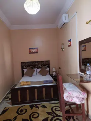 a bedroom with a bed and a table and a chair at Desert Dream Apartment in Merzouga