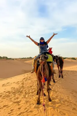 a woman riding a camel in the desert at Desert Dream Apartment in Merzouga