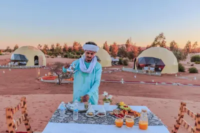 a man standing in front of a table with food at Desert Dream Apartment in Merzouga
