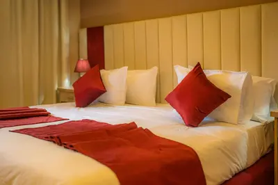 a large bed with red and white pillows at Hôtel Reda Zagora in Zagora