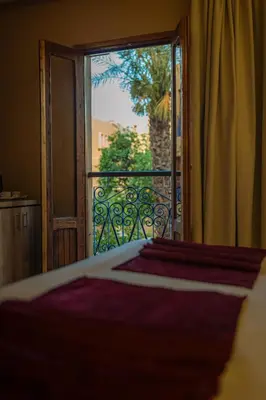 a bedroom with a door open to a balcony at Hôtel Reda Zagora in Zagora