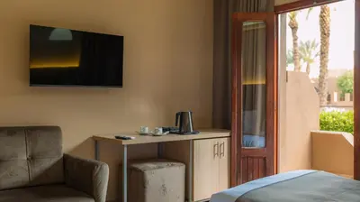 a room with a bed and a table and a chair at Hôtel Reda Zagora in Zagora