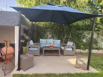 a patio with an umbrella and a couch and chairs at Villa Paradis Fès