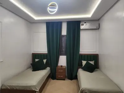 two beds in a room with green curtains at Villa Paradis Fès