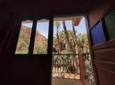 an open door to a balcony with palm trees at Le LAC Auberge Camping Todra in Tinerhir