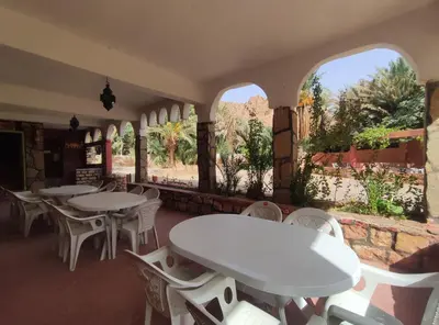 a restaurant with white tables and chairs and windows at Le LAC Auberge Camping Todra in Tinerhir