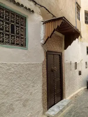 a building with a black door and a window at Maison Soulaîmi in Fès