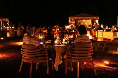 a group of people sitting at a table at night at Sahara Spirit luxury Camp in Merzouga