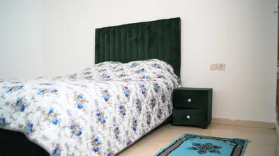 a bedroom with a bed with a green headboard and a night stand at City Center Stay - Résidence Omar 1 by ZenStay in Fès