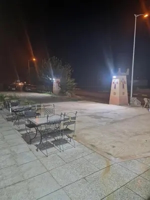 a group of tables and chairs in a park at night at Café restaurant in Issafene